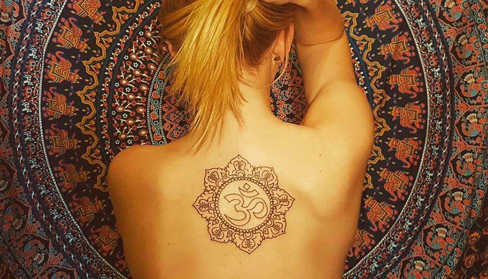Женщина с татуировкой лотоса на спине, символизирующей просветление и чистоту