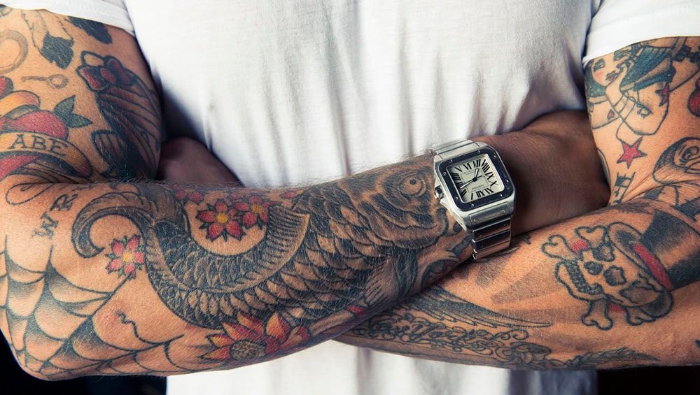 Парень с татуировкой на руке в виде компаса, свидетельствующей о его любви к путешествиям и приключениям.