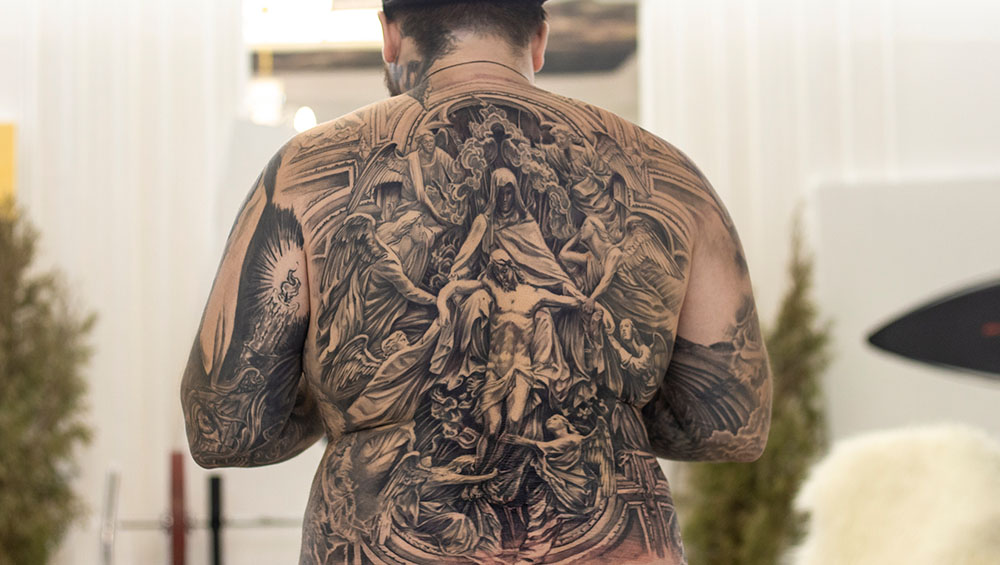 Мужчина с татуировкой на спине в виде дракона, символизирующего мудрость, силу и власть.